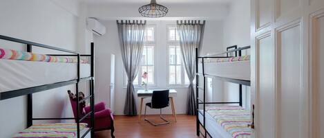A dormitory room with bunk beds, a desk, and a chair.