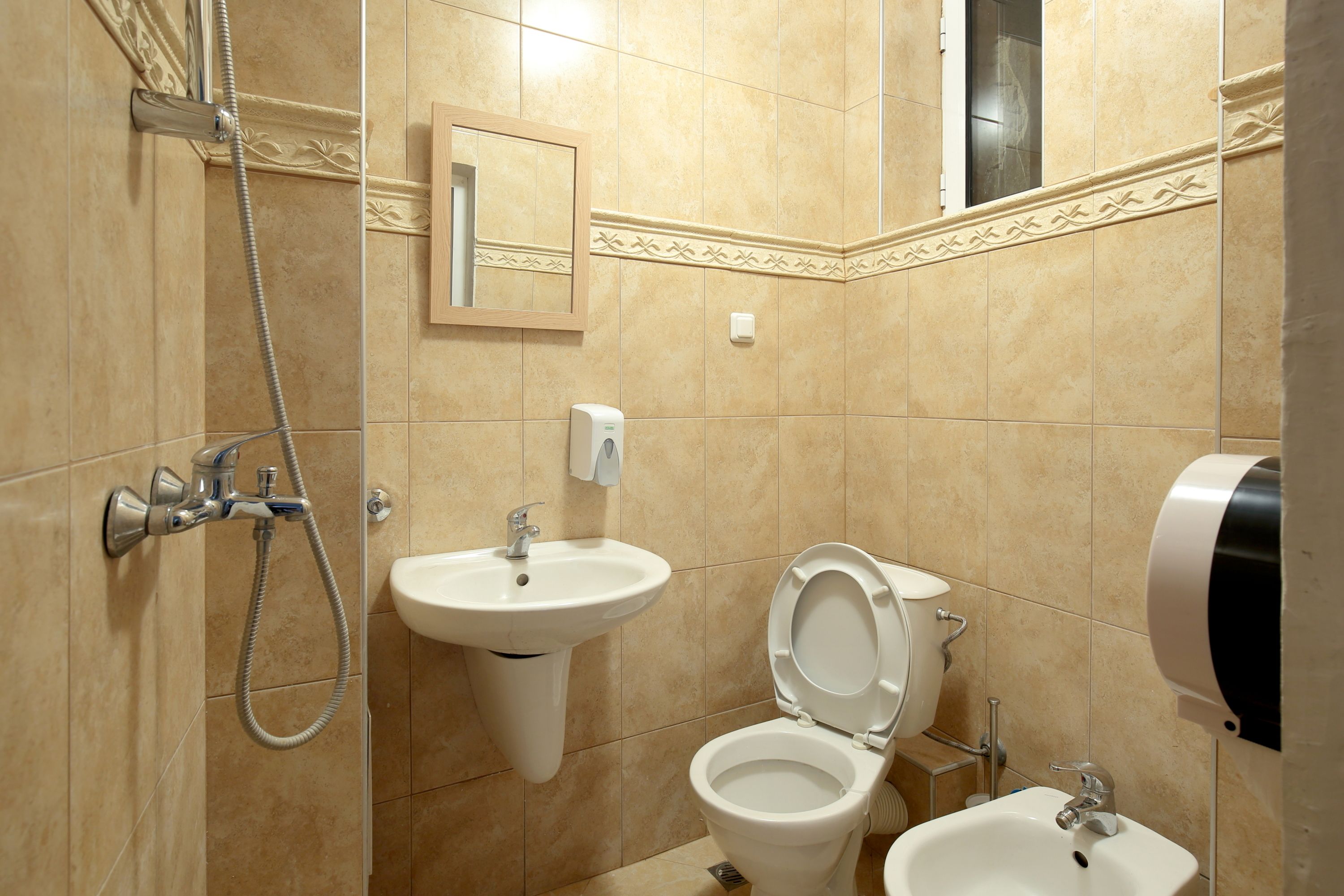 A bathroom with a shower, sink, toilet, and bidet.
