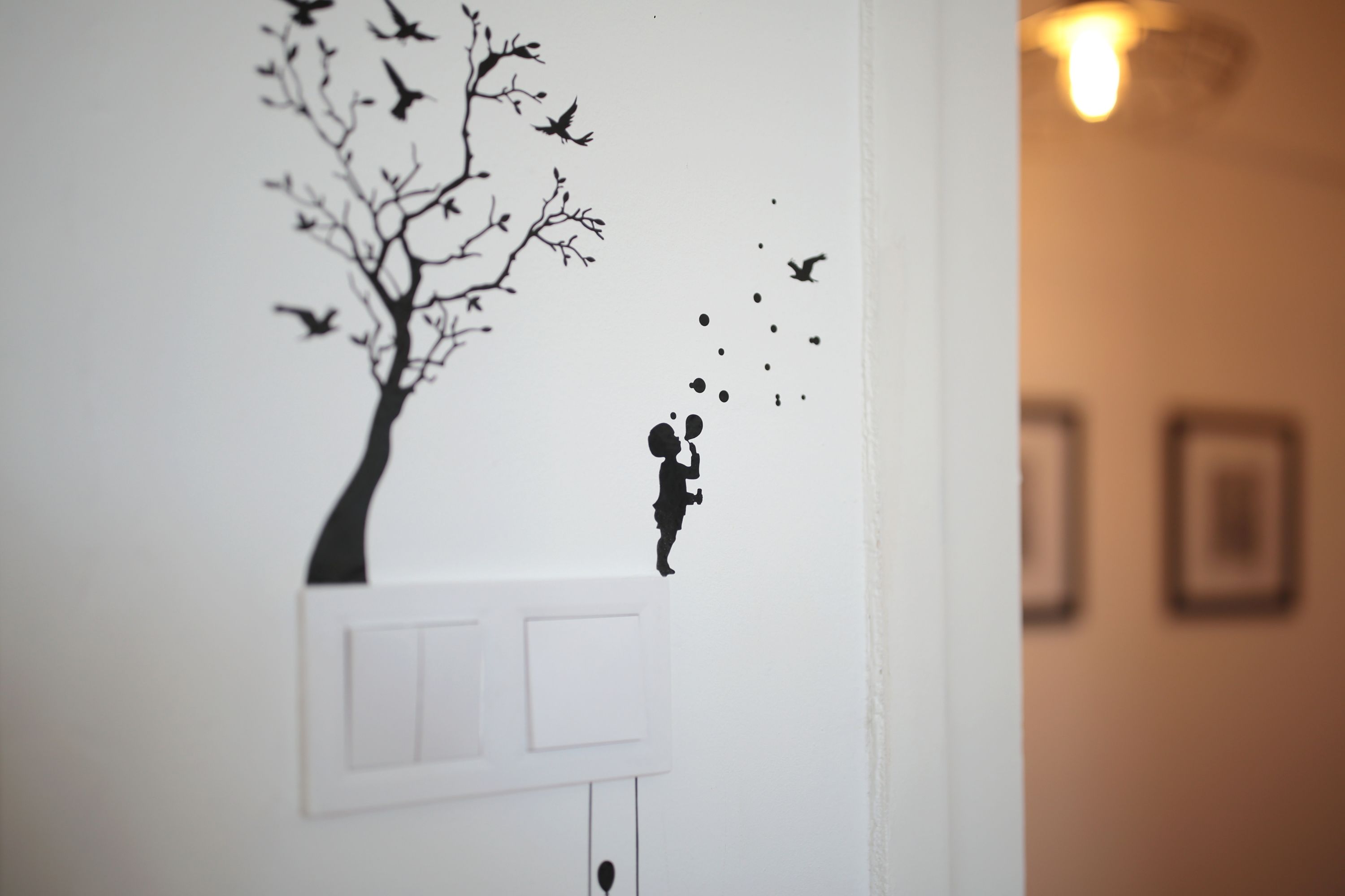 Un adhesivo mural de un árbol con pájaros y un niño.