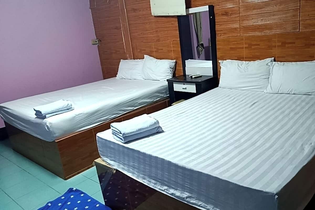 Quarto de hotel com duas camas de solteiro, cabeceira de madeira, mesa de cabeceira com espelho e uma pequena mesa.