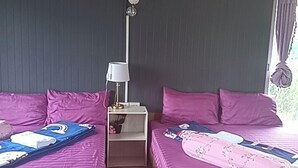 A room with two beds, a nightstand, a lamp, and a fluffy rug.