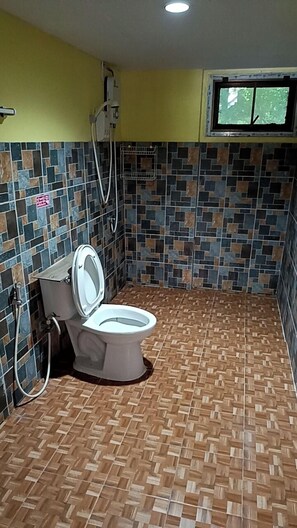 A bathroom with a toilet, a shower, and a window.