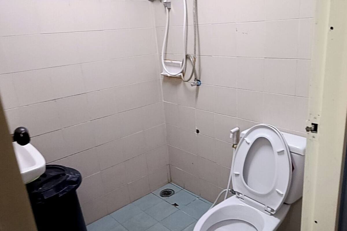 Um banheiro pequeno, com azulejos, contendo um vaso sanitário e um chuveiro.