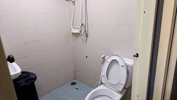 Un baño pequeño con azulejos, un inodoro y una ducha.