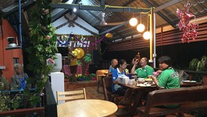 A dining area with wooden tables and benches, surrounded by plants and decorations. - Bussaracum Hotel (Tha Muang)