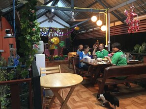 A dining area with wooden tables and benches, surrounded by plants and decorations. - Bussaracum Hotel (Tha Muang)