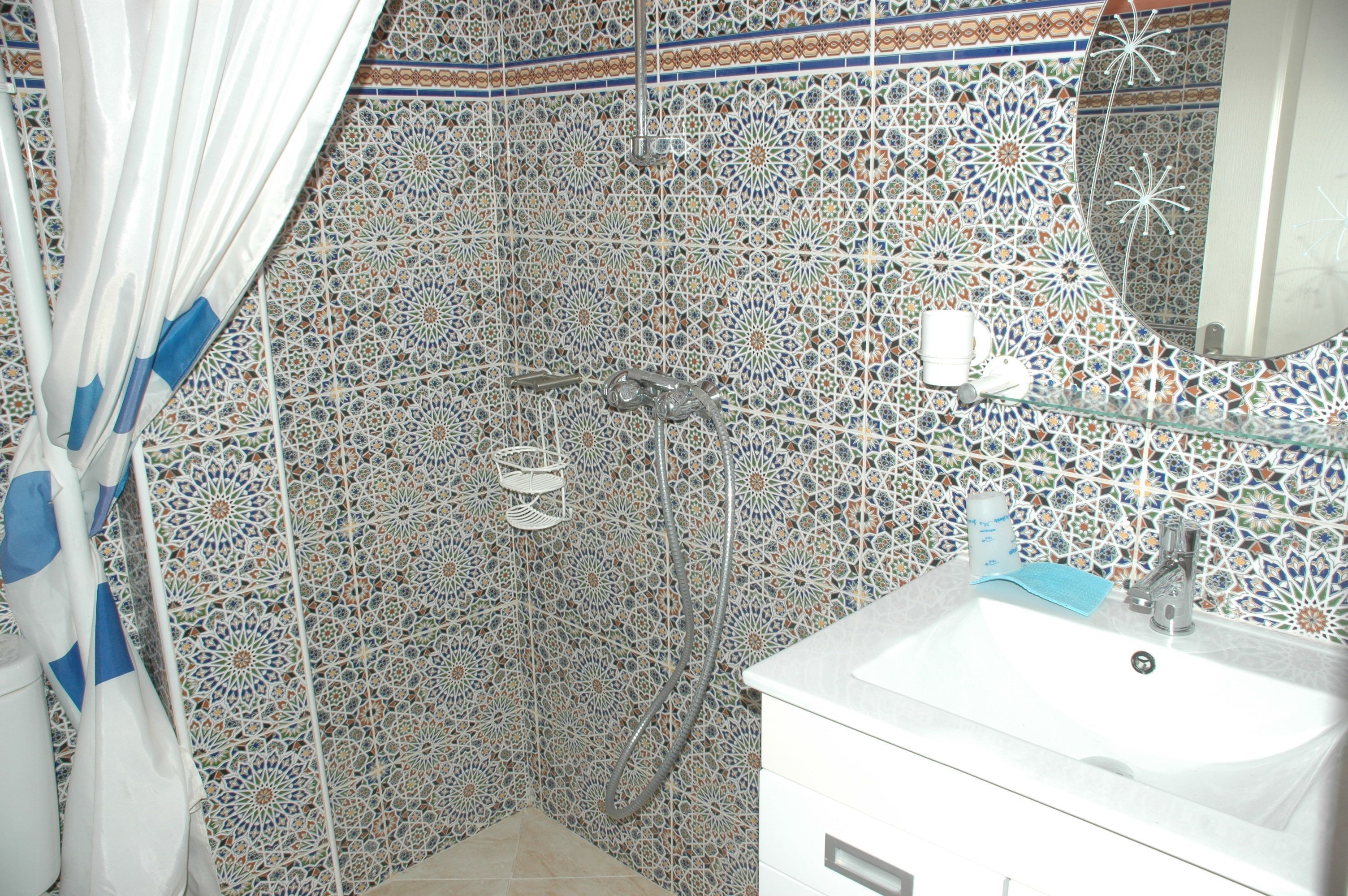 Ein Badezimmer mit Dusche, Waschbecken und dekorativen Fliesenwänden.
