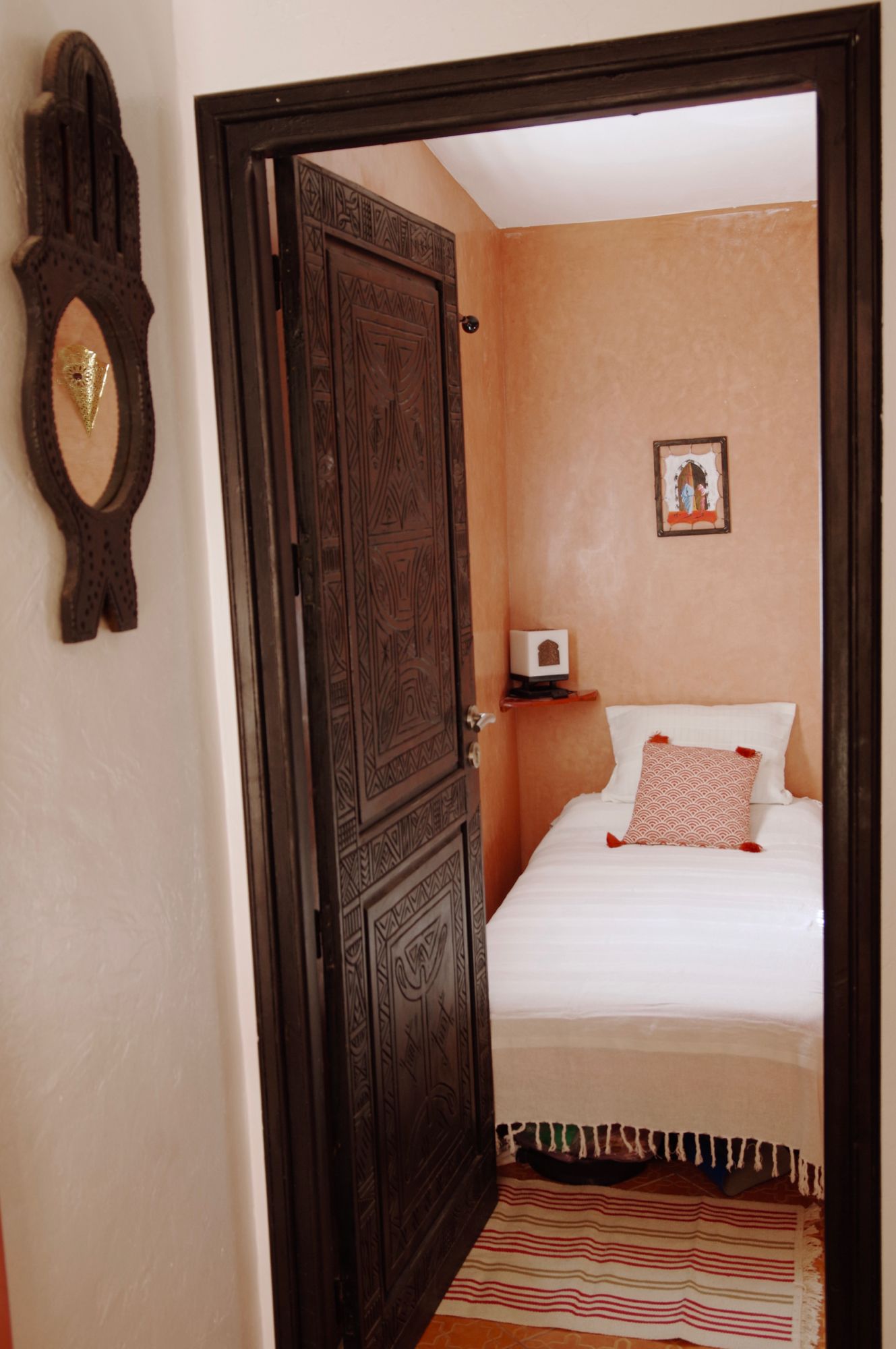 A bedroom with a large bed, a nightstand, a wall-mounted picture, and a decorative mirror.