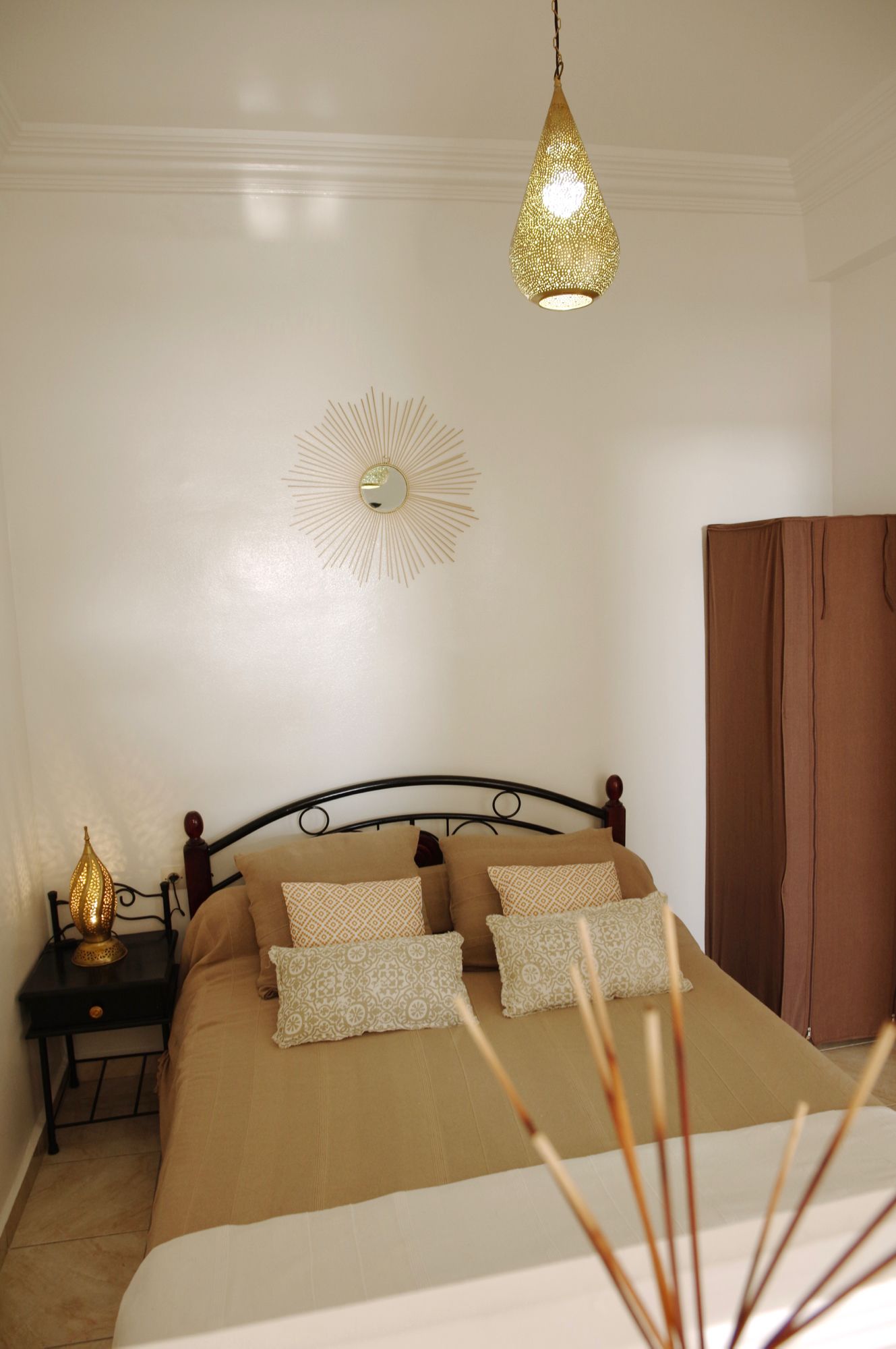 A bedroom with a bed, a nightstand, a lamp, a wall decoration, and a curtain.