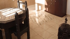 Ein Essbereich mit einem Tisch und Stühlen mit Muster, einer dunklen Holzschrank und einer hängenden Laterne.