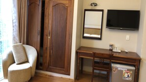 Una habitación con un escritorio de madera, una silla, un televisor y un armario.