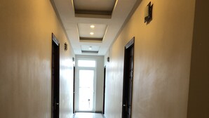 Un pasillo largo y bien iluminado con piso de baldosas brillantes, puertas a ambos lados y una luz intensa al final.