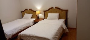 Two single beds with wooden headboards, white bedding, and a bedside lamp. - Dreams Hotel (Da Lat)