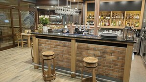 Una zona de bar con mostrador de ladrillo, taburetes y una variedad de botellas y vasos.