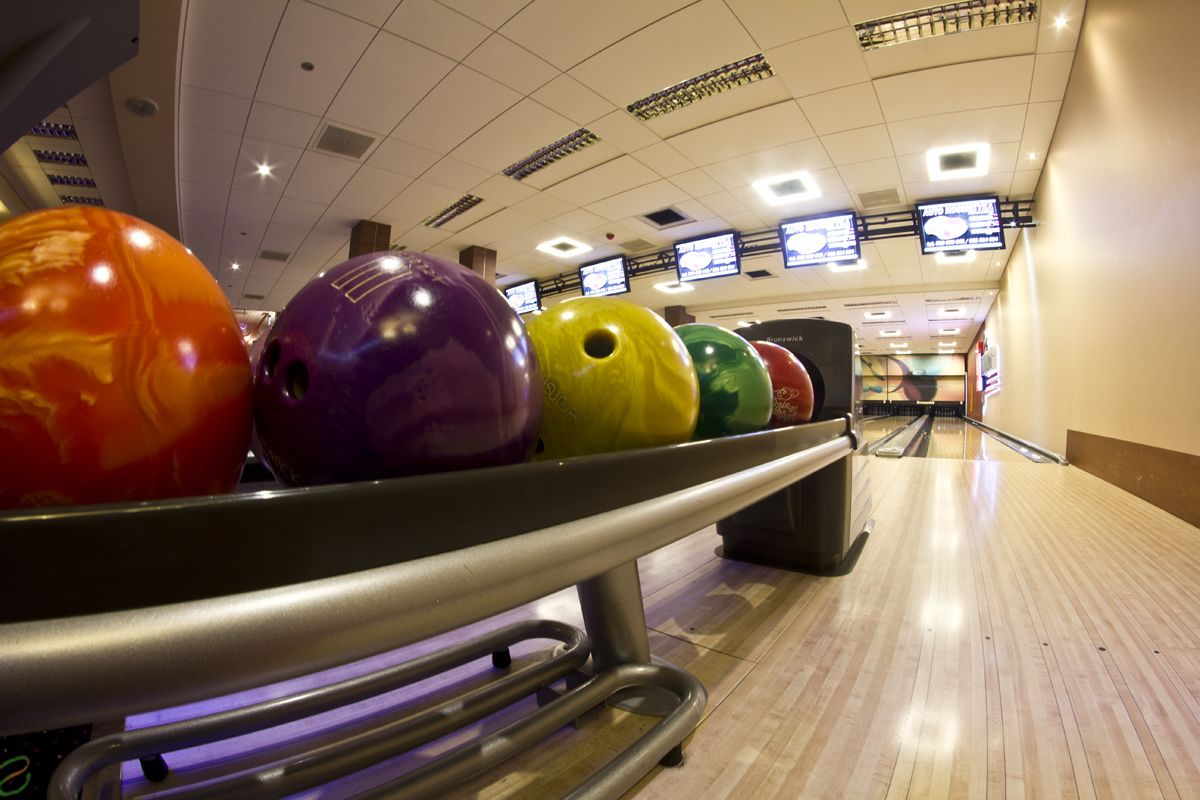 En bowlinghall med flera banor och bowlingklot i olika färger.