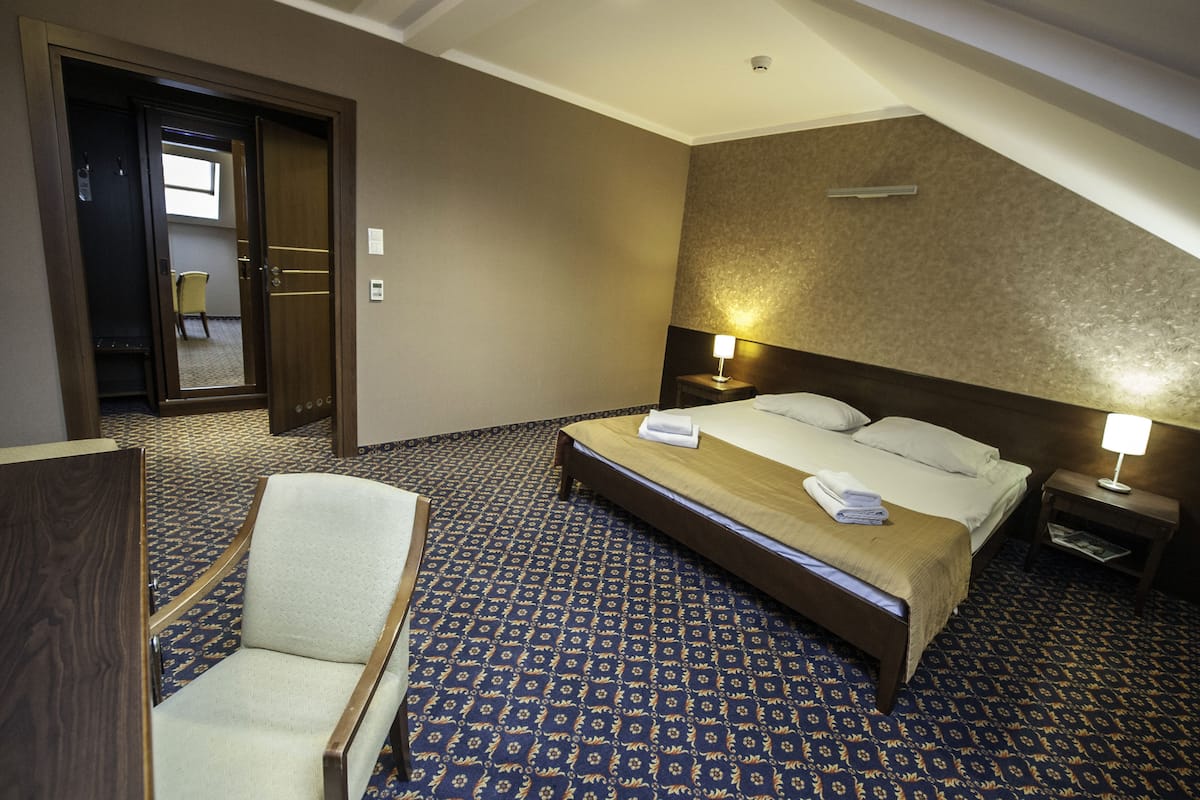 A hotel room with a bed, bedside tables, a chair, and a carpeted floor.