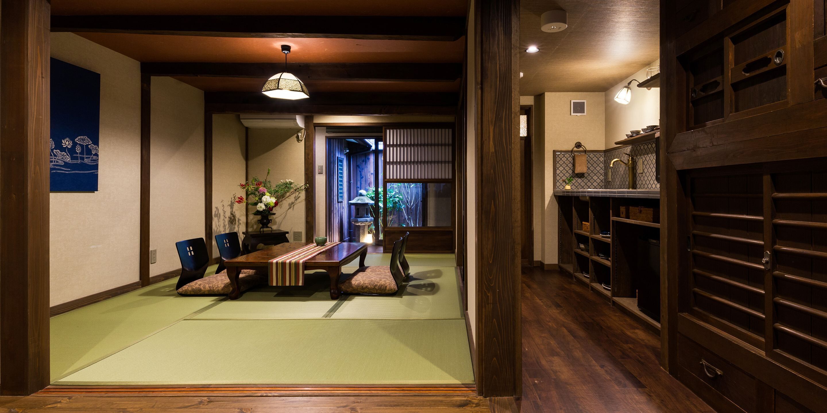 Una habitación tradicional japonesa con suelo de tatami, una mesa de madera baja y una puerta corrediza que da a otra habitación.