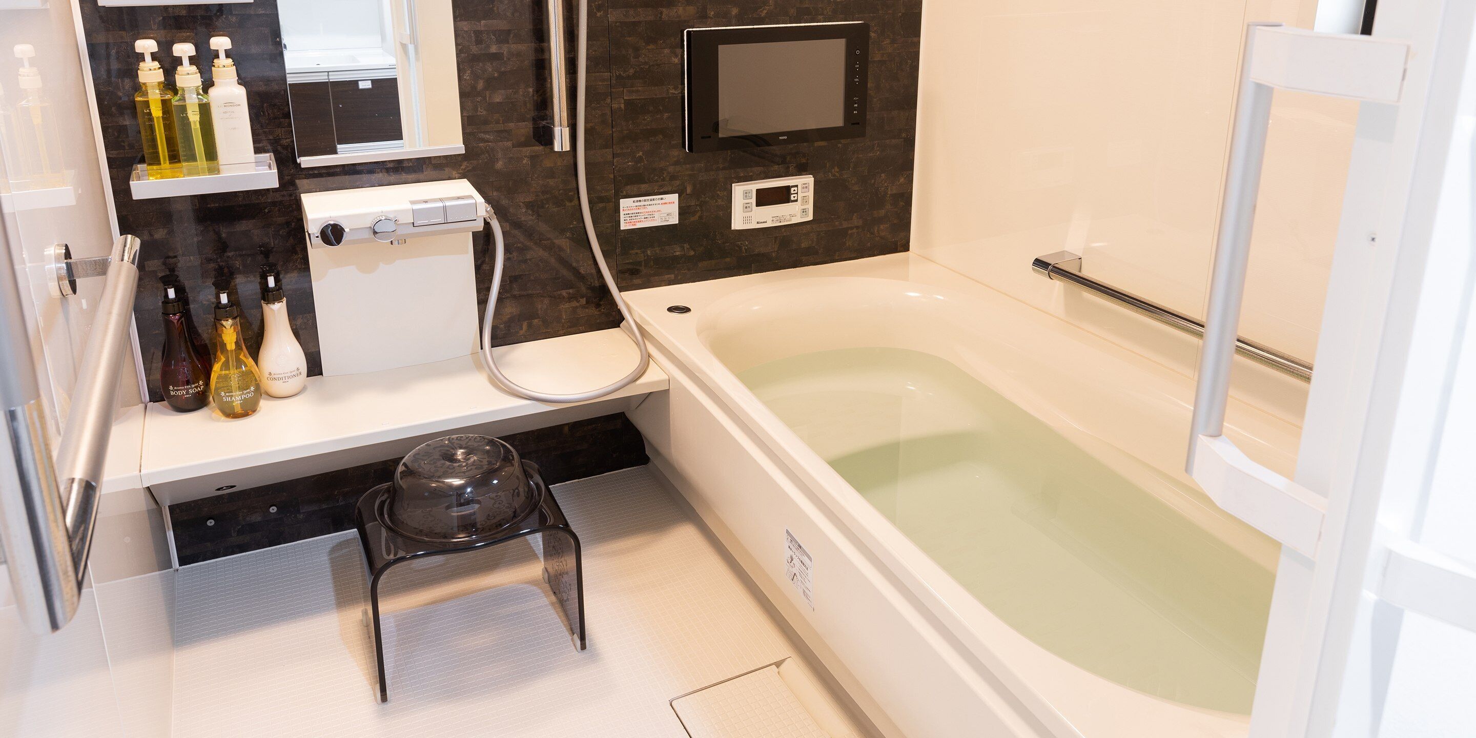Ein modernes Badezimmer mit Badewanne, Dusche und Waschtisch mit Toilettenartikeln.