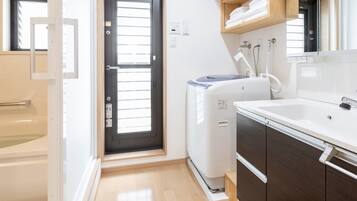 Un baño pequeño con bañera, lavadora compacta e lavabo con espejo.
