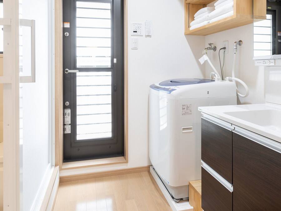 Un baño pequeño con bañera, lavadora compacta e lavabo con espejo.