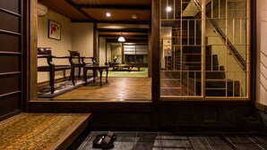 A traditional Japanese interior with tatami flooring, wooden furniture, and a sliding door leading to a staircase. - Kyoisuke (Kyoto)