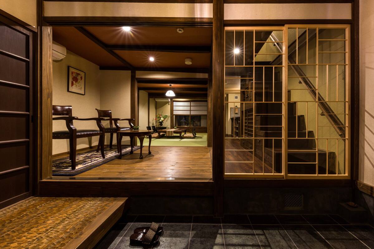 Ein traditionelles japanisches Interieur mit Tatami-Böden, Holzmöbeln und einer verschiebbaren Tür zu einer Treppe.