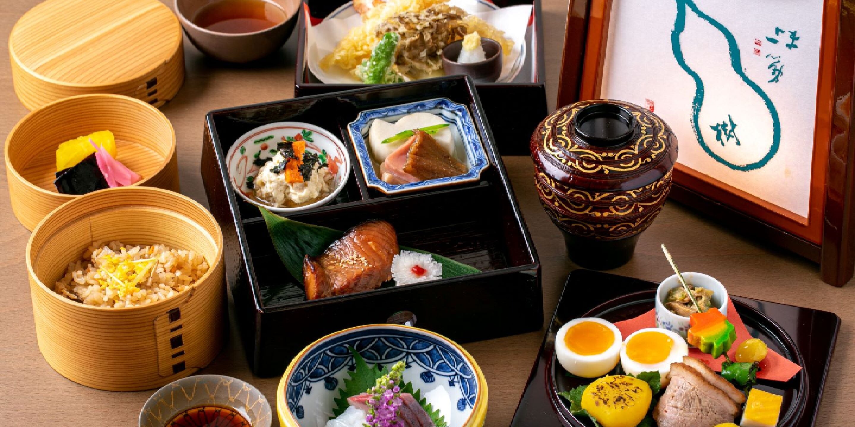 Una variedad de platos tradicionales japoneses dispuestos en una mesa, como sushi, arroz y verduras encurtidas.