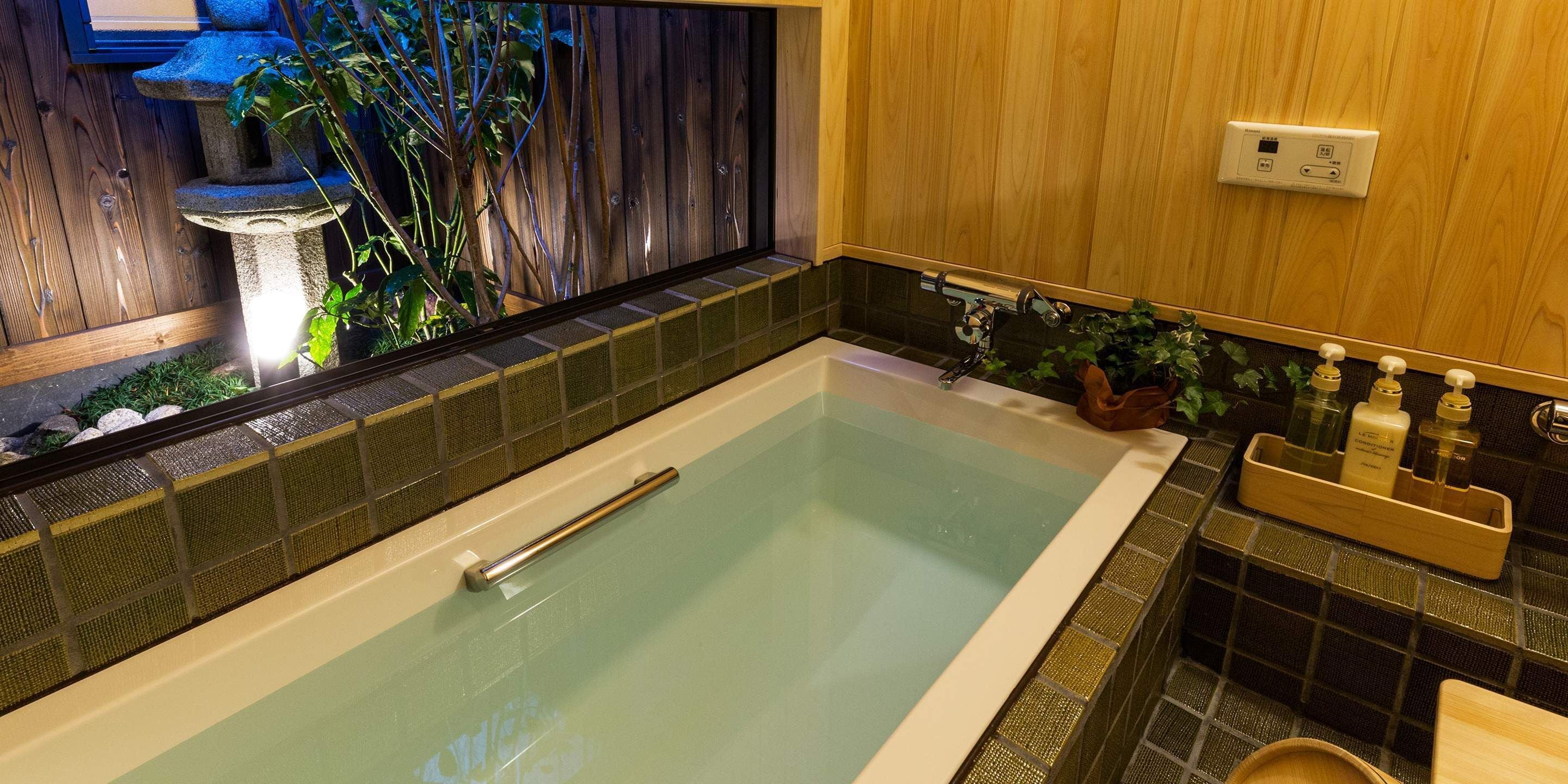 A modern bathroom with a freestanding bathtub, a wooden vanity, and a small plant.