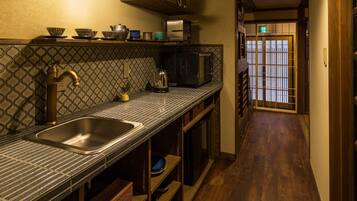 A narrow kitchen with a sink, a microwave, and a kettle on the counter.