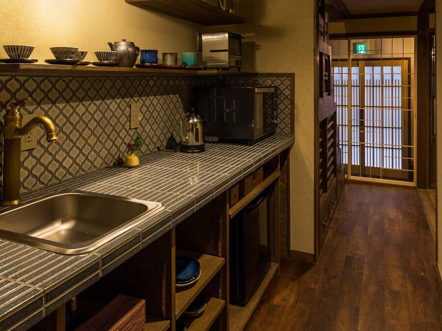 A narrow kitchen with a sink, a microwave, and a kettle on the counter.