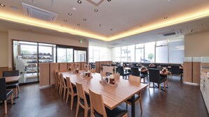 Un comedor moderno con largas mesas y sillas de madera, ventanas amplias y vistas a la ciudad.
