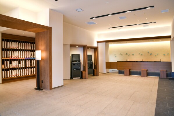 A spacious lobby with a reception desk, a self-service kiosk, and a wall-mounted display.