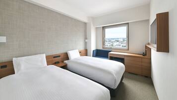 Habitación de hotel con dos camas, un escritorio, una silla, un ventanal grande con vista a la ciudad y un televisor de pared.