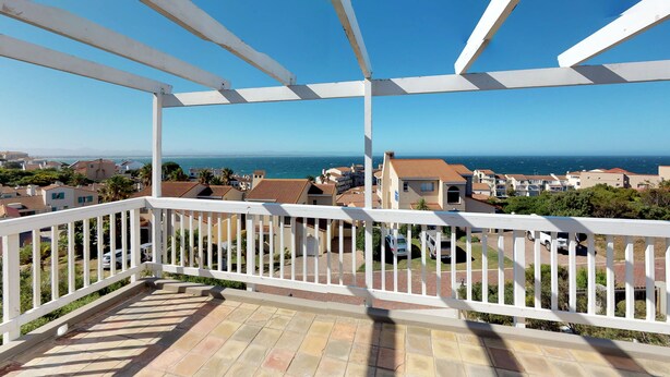 A balcony with a white railing overlooking a residential area with houses and a view of the sea. - Captain's Reach St. Francis Bay (Saint Francis Bay)