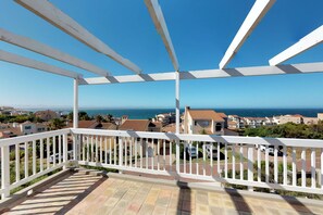 A balcony with a white railing overlooking a residential area with houses and a view of the sea. - Captain's Reach St. Francis Bay (Saint Francis Bay)