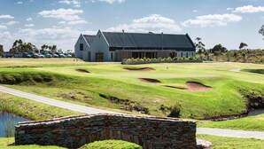 A golf course with a clubhouse, stone bridge, and a pond. - Captain's Reach St. Francis Bay (Saint Francis Bay)