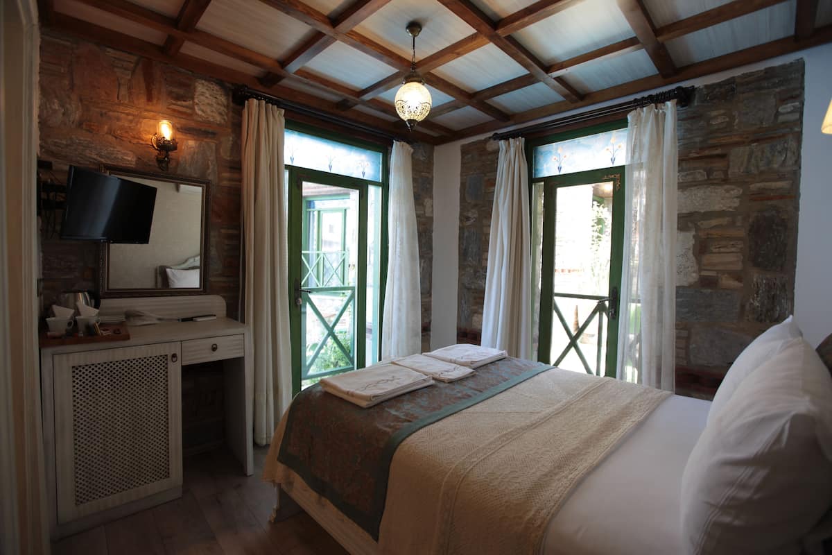 A bedroom with a bed, a dresser, a mirror, and a window with curtains.