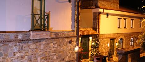 A stone building with a balcony and a door, illuminated by warm lighting.