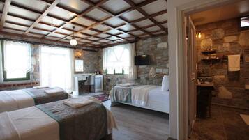 A room with two beds, a stone wall, a television, and a small desk.