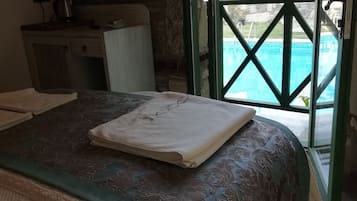 A hotel room with a bed, a desk, a television, and a view of a swimming pool.