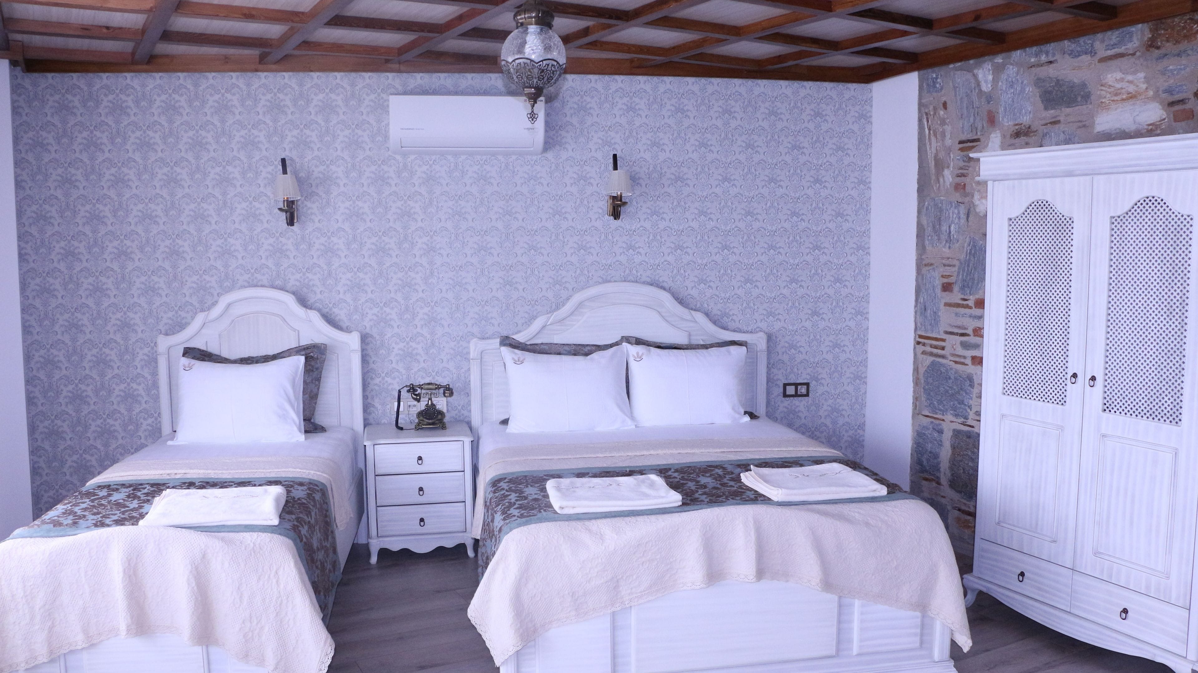 A bedroom with two beds, a wardrobe, and a ceiling fan.