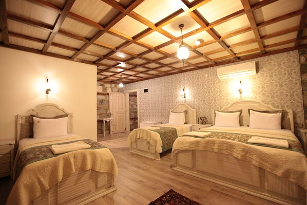 A hotel room with three single beds, wooden beams on the ceiling, and a patterned wallpaper. - Celsus Boutique Hotel (Selçuk)