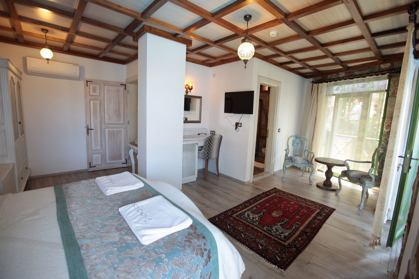 A bedroom with a large bed, a television, a desk, and a chair.