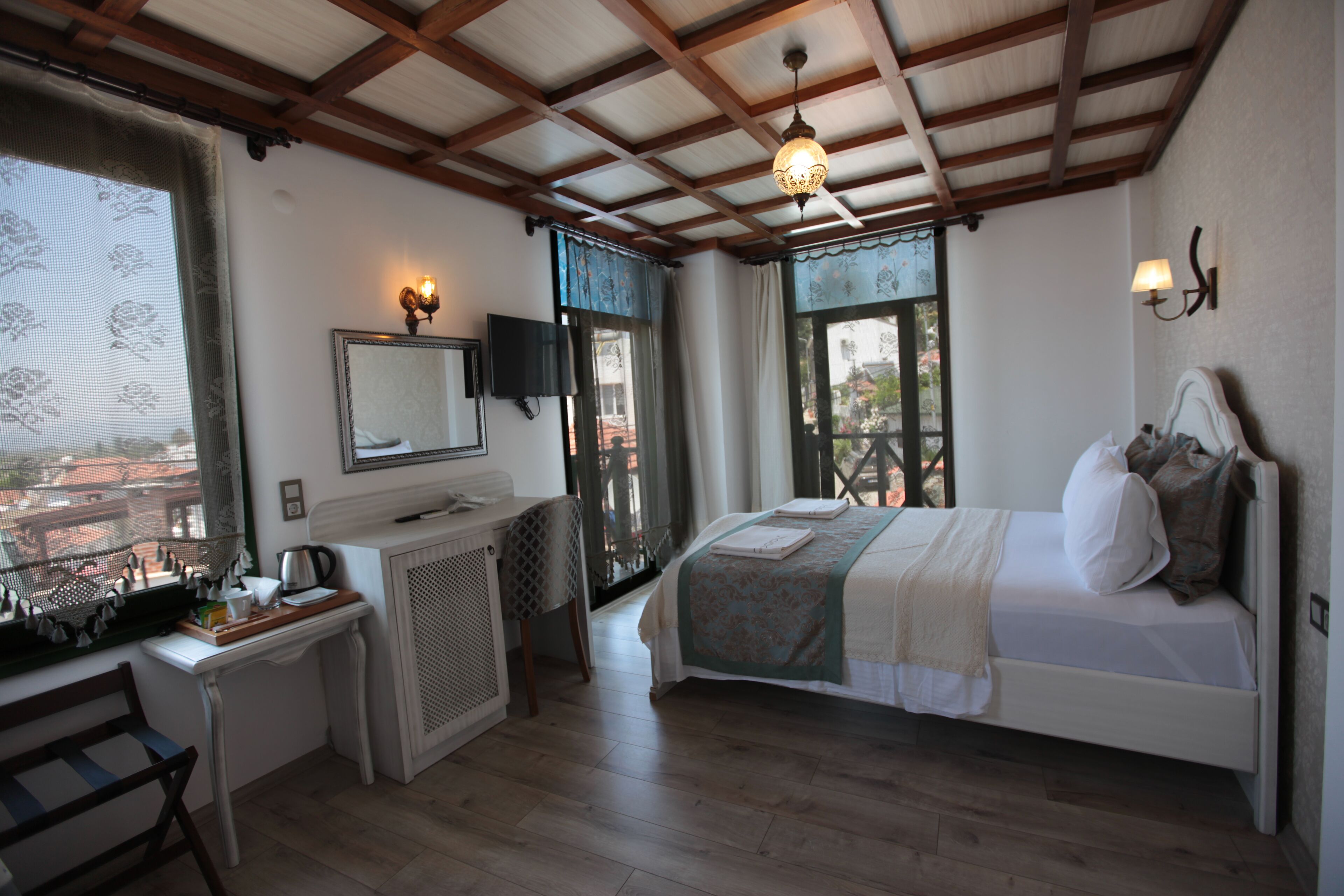 A bedroom with a bed, a desk, a chair, a television, and a window with a view.