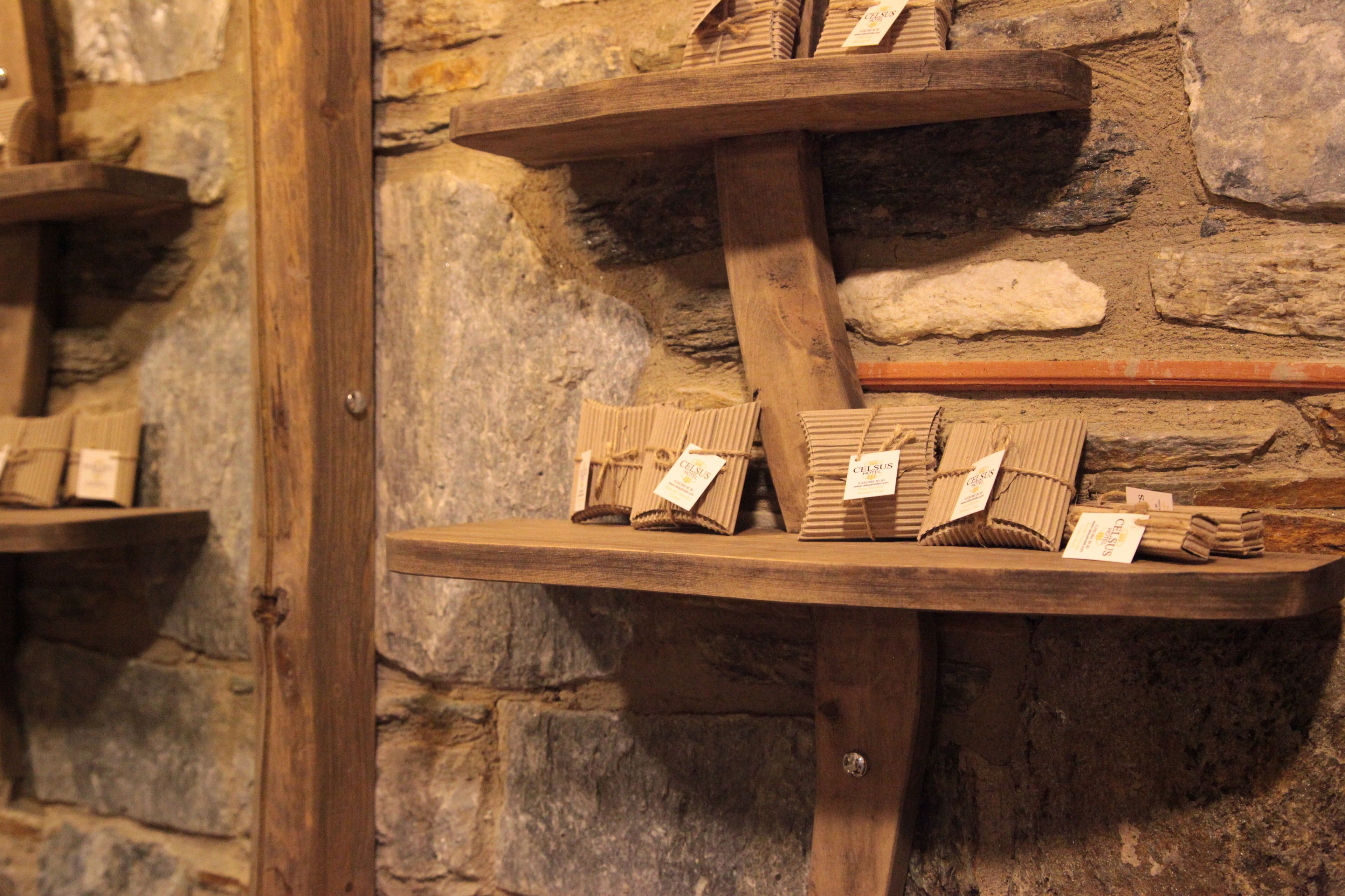 Holzregale mit verpackten Waren an einer Steinwand.