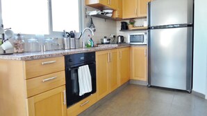 A kitchen with wooden cabinets, a stainless steel refrigerator, a microwave, and a stove. - Super Central Stunning Roof 2BR Apt (Tel Aviv)