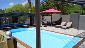 A swimming pool with a wooden deck, a red umbrella, and lounge chairs. - Le Paddock du Val de Lys (Blessy)
