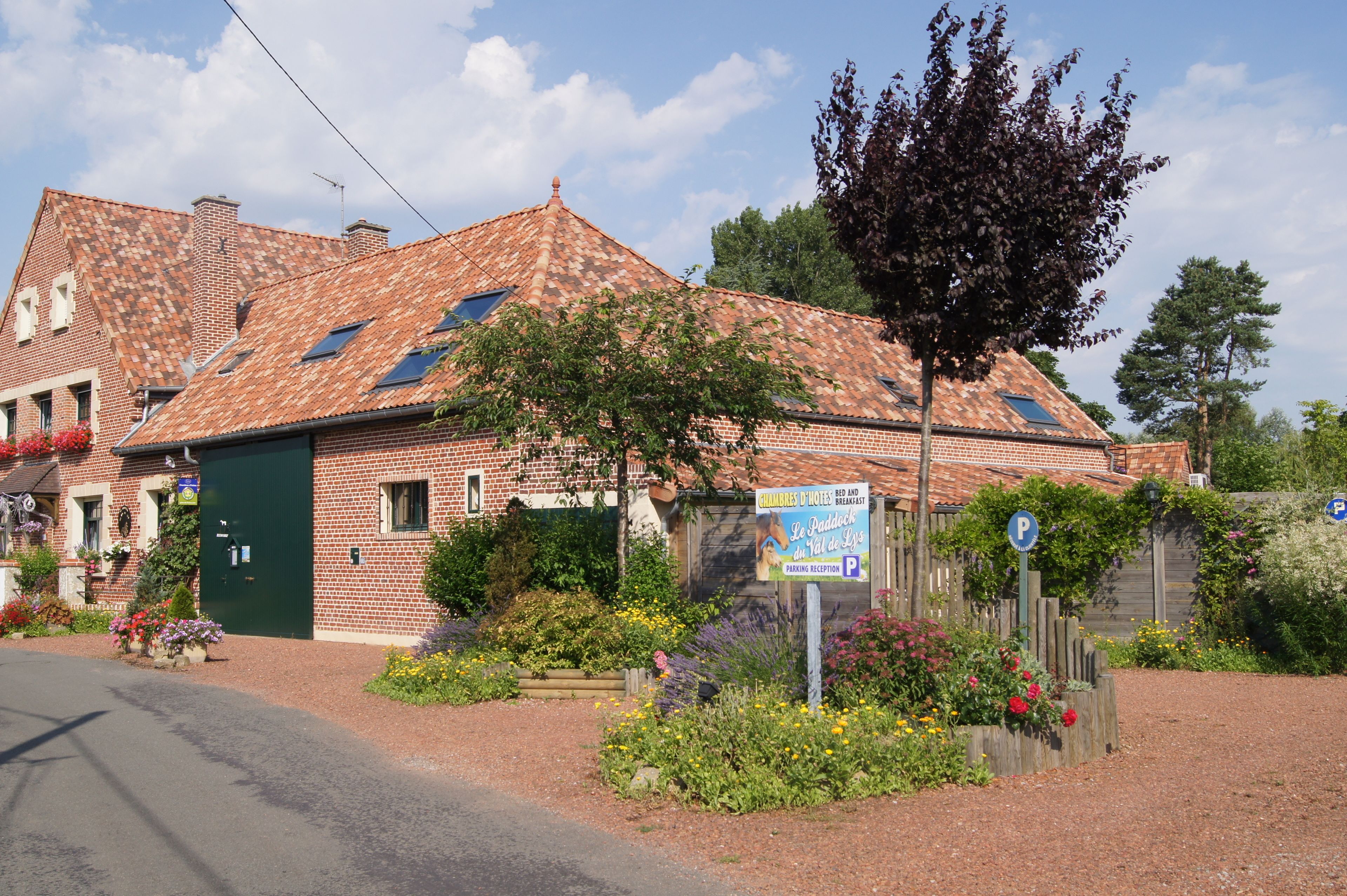 Een klassiek gebouw van baksteen met een pannendak, een groene deur en een bordje dat een ontbijtreceptie aangeeft.