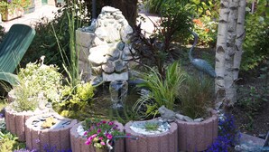 A garden with a pond, stone structures, and various plants. - Le Paddock du Val de Lys (Blessy)