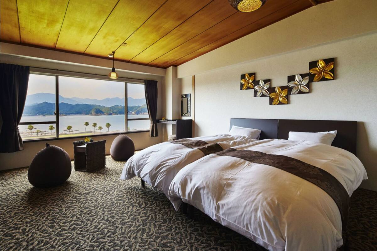 Un cuarto de hotel con una cama grande, vista al mar y techo de madera.